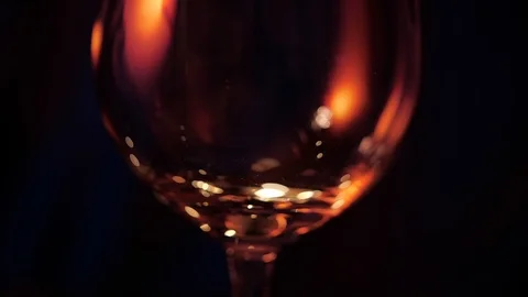 Slow motion close up view of red wine pouring into goblet wineglass over dark Stock Footage 120333492