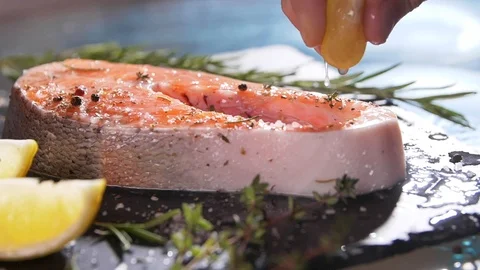 Slow motion close up view of unrecognizable hand squeezing lemon juice on salmon Video stock 107380223