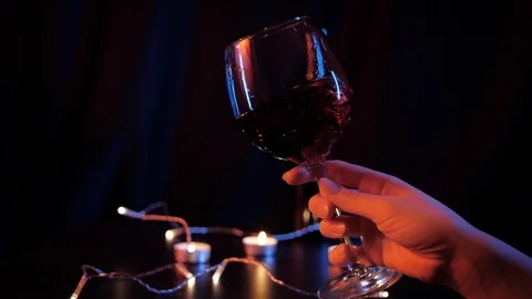 Slow motion close up view of waving red wine in a glass by woman's hand over Stock Footage 120332921