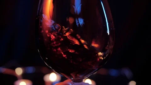 Slow motion close up view of waving red wine in a glass over dark background Stock Footage 120333037