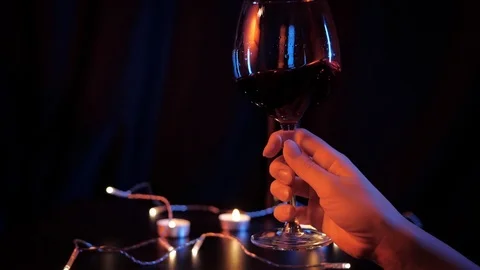 Slow motion close up view of waving red wine in a glass by woman's hand over Stock-Footage 120333240