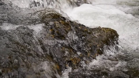 Slow motion close-up of water over river rocks. Stock Footage 99809246
