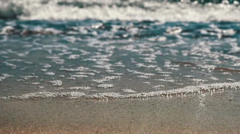 Slow motion close up of waves lapping on red sand beach focus in FG Vídeo Stock 64252735