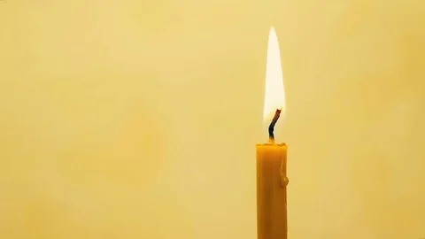 SLOW MOTION: close-up of a wax candle burns on a yellow background. Stock Footage 82297225