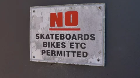 Slow motion close-up of a weathered metal sign reading no skateboards or bikes Stock Footage 346882281