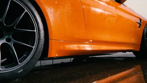 Slow motion close up on wet wheel of orange sports car speeding forward Stock Footage 101812934