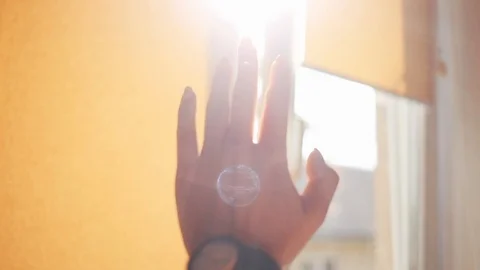 Slow motion close up of a woman's hand raises to the sun playing with the sun in Stock Footage 94235800