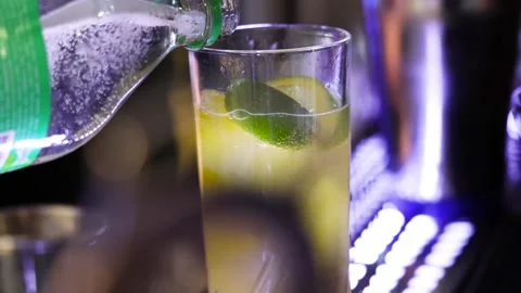 Slow Motion Close Up of Yellow Drink Being Filled with Ice and Lime 動画素材 327482753