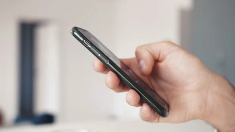 Slow-motion close up of a young man hands using a smartphone phone in a home or Stock Footage 138903513
