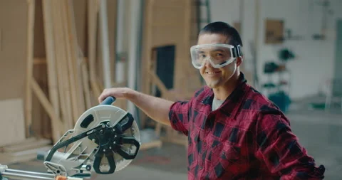 Slow motion close up of a young woodworker with goggles looking at the camera Stock Footage 199622235