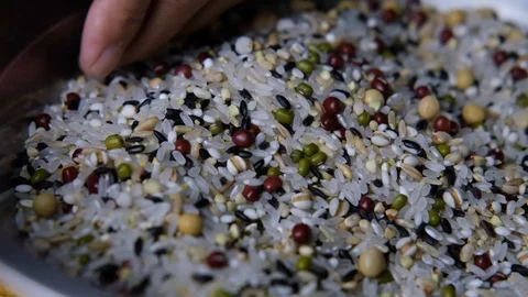 Slow motion: Closeup of beans and rice fall from a senior Chinese woman's hands Stock Footage 128428311