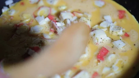 Slow motion closeup clip of man stirring scrambled eggs still raw with Stock Footage 105352694