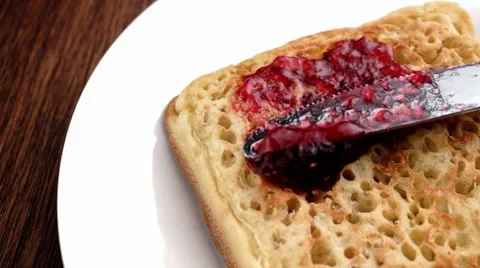 Slow motion closeup of delicious jam being spread on English crumpet Stock Footage 46879682