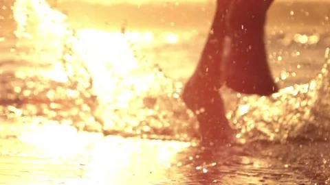 SLOW MOTION CLOSEUP LENS FLARE Active man running on beach splashing ocean water Stock Footage 79082281