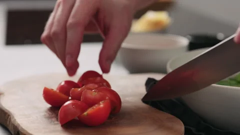 Slow motion closeup man cut cherry tomatoes in halves on olive board Stock Footage 303797957