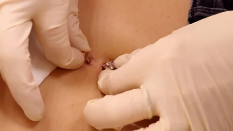 Slow motion closeup master puts belly button ring into navel Stock Footage 102356485