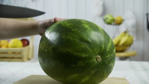 Slow motion closeup of person with large knife slicing watermelon in half - Stock Footage 341236743