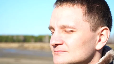 Slow motion closeup portrait of guy young man who frown enjoy sun outdoor Stock Footage 89621092