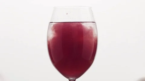 Slow motion closeup poured blueberry juice into water in wine glass Stock Footage
