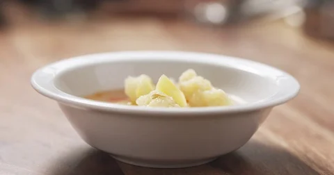 Slow motion closeup pouring cauliflower soup into bowl on wood table Stock Footage