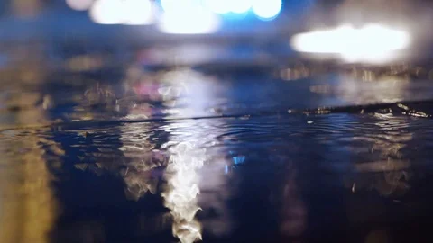 Slow motion closeup Rain drops Falling On puddle with lights reflection on city Stock Footage 121290880