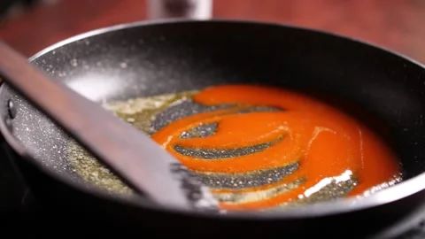Slow motion closeup of red sauce and butter being slowly stirred in a pan Stock Footage 132976337