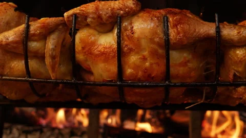 Slow motion closeup of a Roasted chickens on spit grilled over wood fire on big Stock Footage 199262000