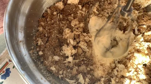 Slow motion closeup of rotating whisks mixing bread and egg dish in bowl Stock Footage 129784951