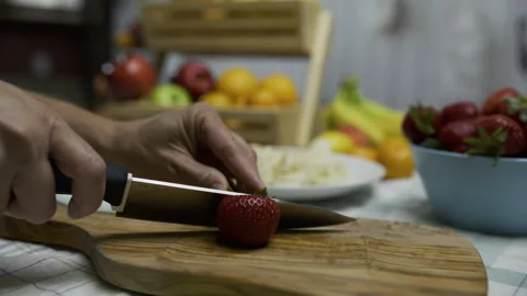 Slow motion closeup shot of knife cutting up strawberry on wooden board Stock Footage 341231008