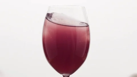 Slow motion closeup swirl poured blueberry juice into water in wine glass Stock Footage