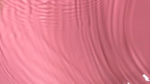 Slow motion closeup water surface texture splash and ripples on pink background Stockbeeldmateriaal 167577763