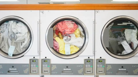 Slow motion of clothes being dried in the dryers at a local laundromat Stock Footage 248859507