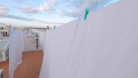Slow motion of clothes hanging on clothes line on a roof during a beautiful d Stock Footage 136097364