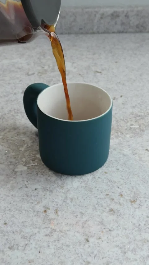 Slow motion coﬀee being poured into blue mug at home Stock Footage 311532822