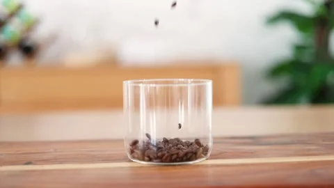 Slow Motion Coffee Bean Dropping into Full Glass Cup 库存影片 253393133