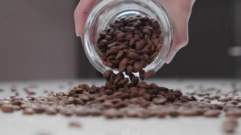 Slow Motion Coffee Beans Falling from Glass Jar in Hand Stock Footage 330538803