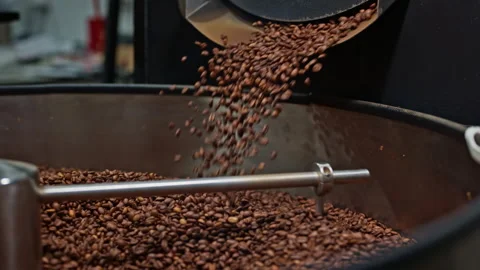 Slow motion coffee beans flowing into a cooling tray after roasting. Stock Footage 327394847