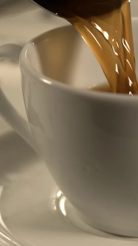 Slow motion coffee being poured into a white cup with warm light and a cozy tabl Video stock 336442837