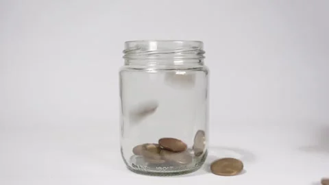 Slow motion of coins falling into a glass jar until it is full Stock Footage 317109345