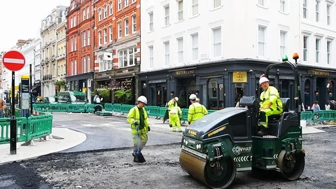 Slow motion of Conway construction workers paving road in London, UK Stock Footage 106715639