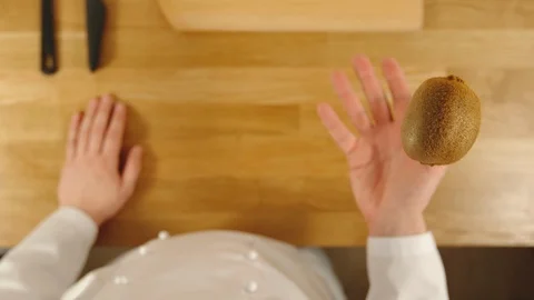 SLOW MOTION: Cook throws up kiwi and catches it - Top View Stock Footage 99082878