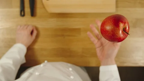 SLOW MOTION: Cook throws up red apple and catches it - Top View Stock Footage 99087304