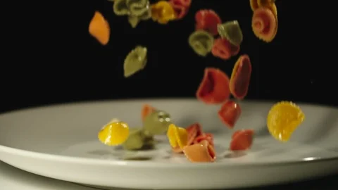 SLOW MOTION: Cooked color figural pasta fall into white empty plate Stock Footage 100632040