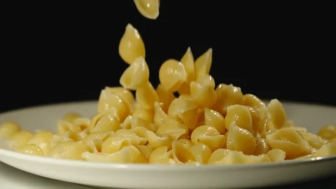 SLOW MOTION: Cooked conchiglie fall into full plate Stock Footage 100632058