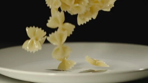 SLOW MOTION: Cooked farfalle fall into white empty plate Vídeo Stock 100631919
