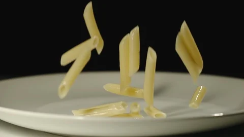 SLOW MOTION: Cooked penne rigate fall into white empty plate Stock Footage 100631950