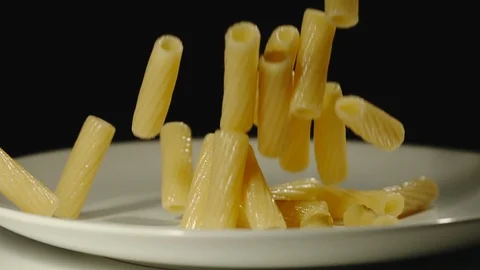SLOW MOTION: Cooked tortiglioni fall into white empty plate Stock Footage 100632027