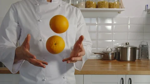 SLOW MOTION: Cooker juggles an oranges in a kitchen Vídeo Stock 129021761