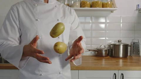 SLOW MOTION: Cooker juggles two potatoes in a kitchen Stock Footage 129020329