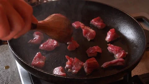 Slow motion cooking small pieces of meat in the pan splashing oil Stock Footage 199636376
